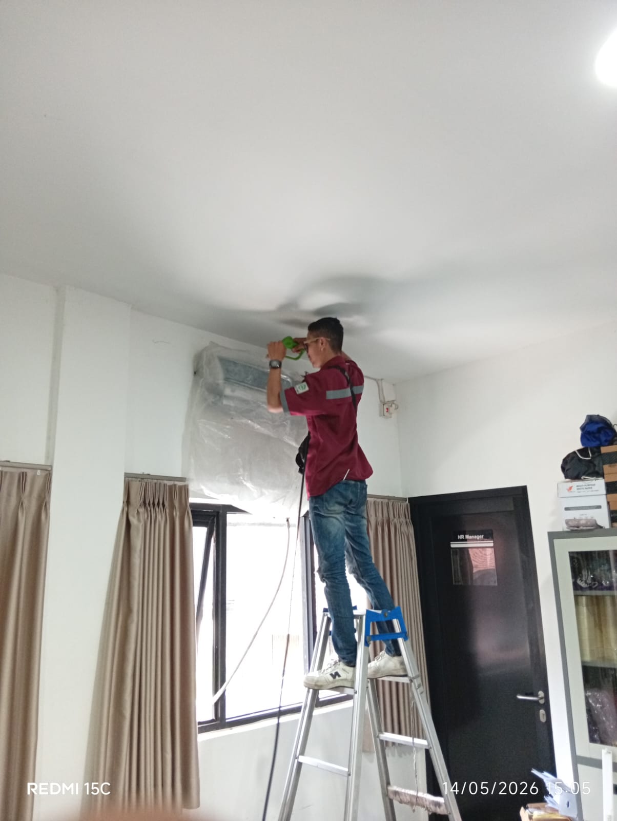 Teknisi membersihkan unit indoor AC